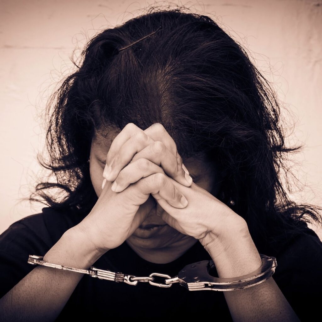 Woman in handcuffs hiding her face